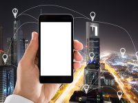 88244922 - hand holding mobile phone with blank white screen in front of city showing location pointers